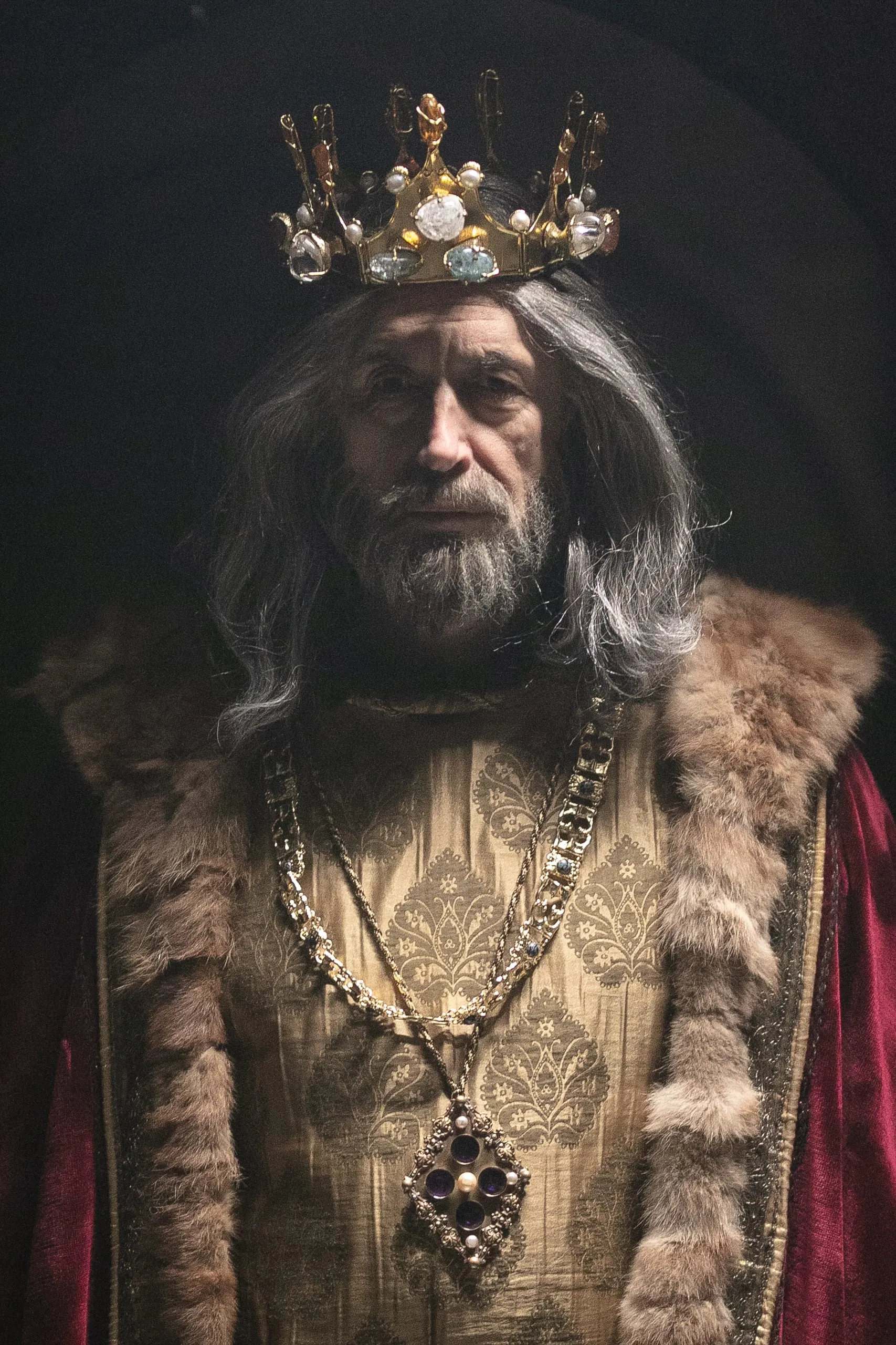 Portrait of an ageing king in a gold crown, brocade robe and heavy chains across his chest